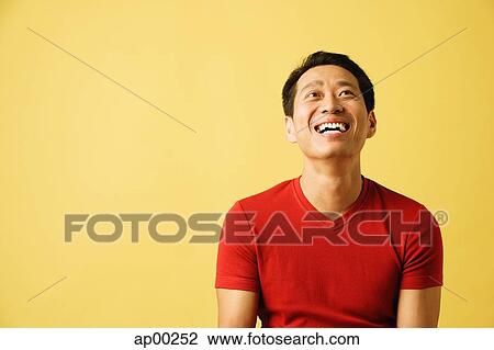 Stock Image - Man smiling, looking up, portrait. Fotosearch