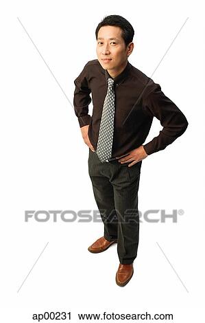 Stock Image - Man standing with hands on hips, looking at camera. Fotosearch