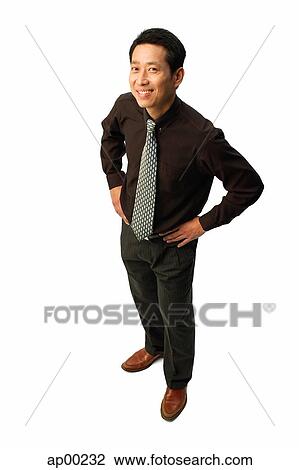 Stock Image - Man standing with hands on hips, smiling at camera. Fotosearch