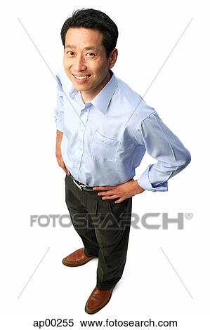 Stock Photography - Man standing with hands on hips, smiling at camera. Fotosearch