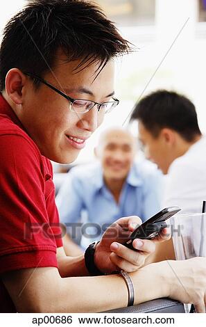 Man using mobile phone, people in the background View Large Photo Image Stock Photograph - Man using mobile phone, people in the background. Fotosearch