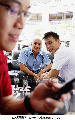 Man watching his friend using mobile phone, focus on the background View Large Photo Image Stock Photo - Man watching his friend using mobile phone, focus on the background. Fotosearch