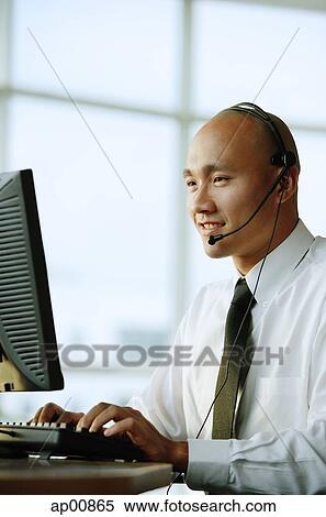 Man with headset, in front of computer, smiling View Large Photo Image Stock Photography - Man with headset, in front of computer, smiling. Fotosearch