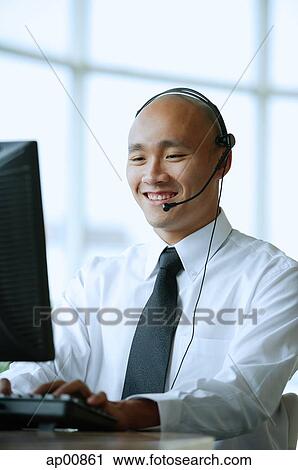 Man with headset, smiling, using computer View Large Photo Image Stock Image - Man with headset, smiling, using computer. Fotosearch