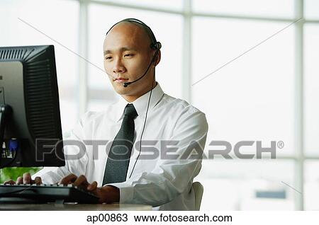 Man with headset, using desktop PC View Large Photo Image Stock Image - Man with headset, using desktop PC. Fotosearch