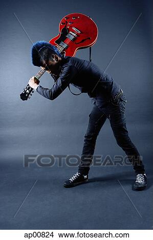 Man with mohawk, holding guitar, over shoulder, bending down View Large Photo Image Picture - Man with mohawk, holding guitar, over shoulder, bending down. Fotosearch