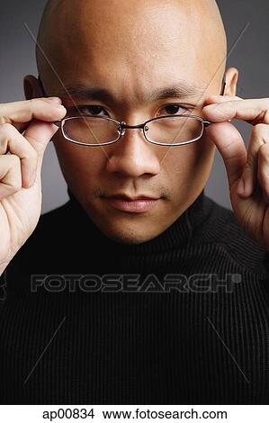Man with shaved head, adjusting glasses, looking at camera View Large Photo Image Picture - Man with shaved head, adjusting glasses, looking at camera. Fotosearch