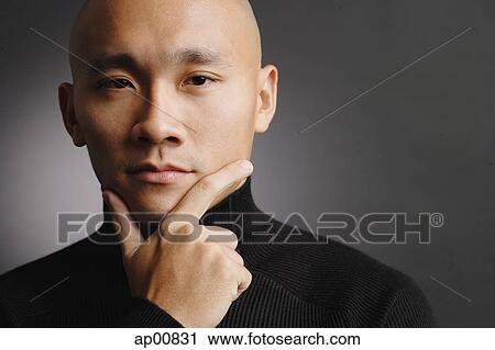 Stock Image - Man with shaved head, hand on chin, portrait. Fotosearch