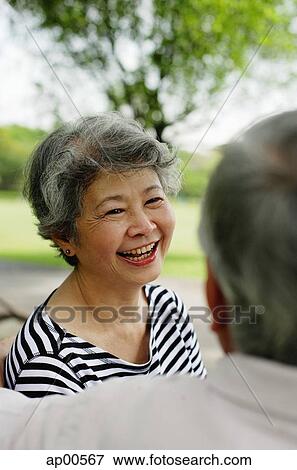 Stock Photo - Mature couple facing, woman wearing striped shirt, smiling. Fotosearch
