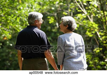 Stock Photo - Mature couple, holding hands, rear view. Fotosearch