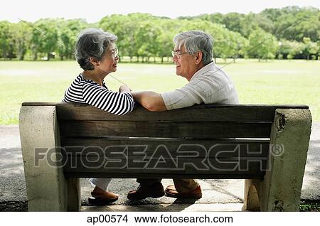 Picture - Mature couple sitting face to face on park bench. Fotosearch