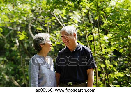 Stock Image - Mature couple, standing side by side, smiling, portrait. Fotosearch