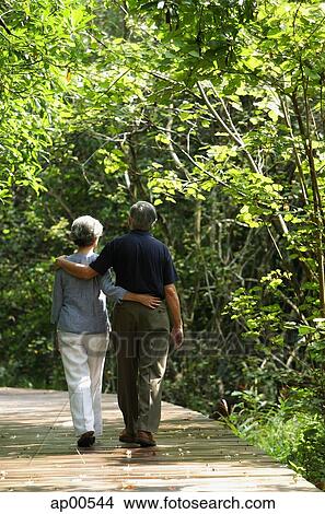 Mature couple walking through park, rear view View Large Photo Image Picture - Mature couple walking through park, rear view. Fotosearch