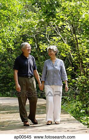 Stock Photography - Mature couple walking through park, holding hands. Fotosearch
