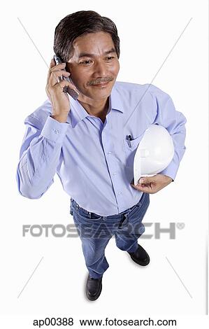 Mature man holding construction hat, using mobile phone View Large Photo Image Stock Photo - Mature man holding construction hat, using mobile phone. Fotosearch