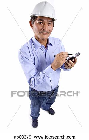 Mature man wearing construction hat, using PDA, looking at camera View Large Photo Image Stock Photo - Mature man wearing construction hat, using PDA, looking at camera. Fotosearch