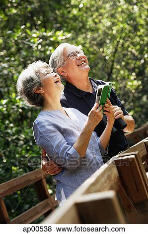 Senior couple side by side, looking up, woman holding book View Large Photo Image Stock Photo - Senior couple side by side, looking up, woman holding book. Fotosearch