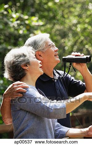 Senior couple side by side, man holding binoculars View Large Photo Image Stock Photo - Senior couple side by side, man holding binoculars. Fotosearch