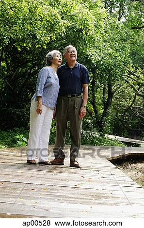 Senior couple standing in park, side by side View Large Photo Image Stock Photo - Senior couple standing in park, side by side. Fotosearch