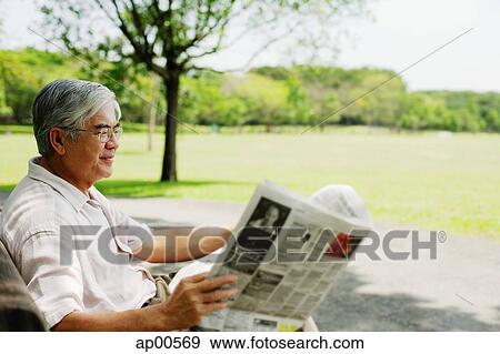 Senior man sitting in park reading newspaper View Large Photo Image Stock Photo - Senior man sitting in park reading newspaper. Fotosearch