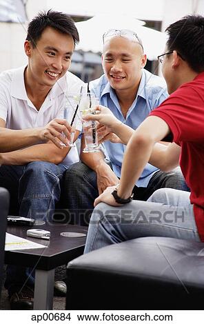 Three guys at a cafe, toasting with drinks View Large Photo Image Picture - Three guys at a cafe, toasting with drinks. Fotosearch