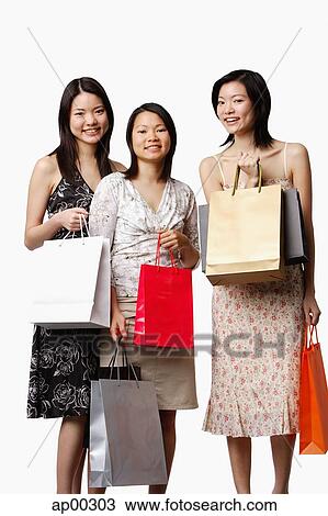 Stock Image - Three young women holding shopping bags. Fotosearch