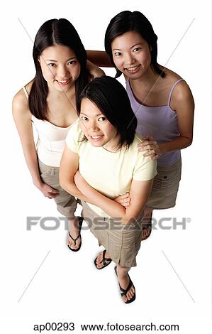 Stock Image - Three young women, looking up at camera, portrait. Fotosearch