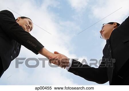 Two businesswoman shaking hands, low angle view View Large Photo Image Stock Photography - Two businesswoman shaking hands, low angle view. Fotosearch
