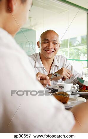 Two men at a cafe, over the shoulder view View Large Photo Image Stock Photo - Two men at a cafe, over the shoulder view. Fotosearch