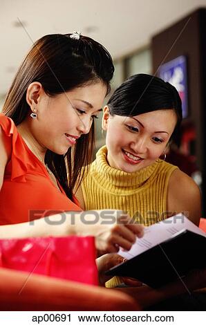 Stock Image - Two women looking at a book. Fotosearch