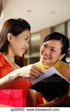 Two women looking at each other, one holding book View Large Photo Image Stock Image - Two women looking at each other, one holding book. Fotosearch