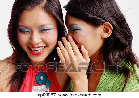 Two women, one looking downwards, the other whispering in her ear View Large Photo Image Stock Photo - Two women, one looking downwards, the other whispering in her ear. Fotosearch