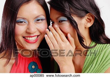 Two women, one smiling at camera, the other whispering to her View Large Photo Image Stock Photography - Two women, one smiling at camera, the other whispering to her. Fotosearch