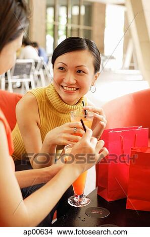 Two women sitting, having drinks View Large Photo Image Picture - Two women sitting, having drinks. Fotosearch