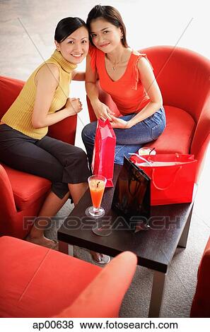 Two women sitting side by side, looking up at camera, portrait View Large Photo Image Stock Photo - Two women sitting side by side, looking up at camera, portrait. Fotosearch