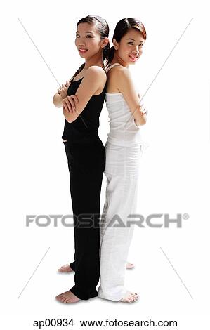 Two women standing back to back, arms crossed, looking at camera View Large Photo Image Picture - Two women standing back to back, arms crossed, looking at camera. Fotosearch