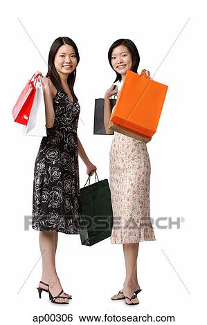 Two young women carrying shopping bags, looking at camera View Large Photo Image Stock Photograph - Two young women carrying shopping bags, looking at camera. Fotosearch