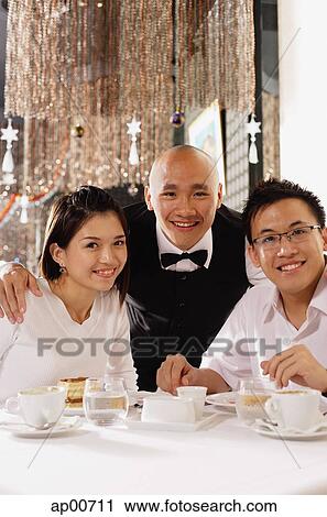 Stock Image - Waiter and customers at restaurant, looking at camera, smiling. Fotosearch