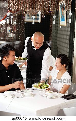 Stock Photography - Waiter serving couple at restaurant. Fotosearch