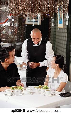 Waiter talking to couple at restaurant View Large Photo Image Stock Photograph - Waiter talking to couple at restaurant. Fotosearch