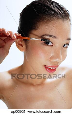Woman applying mascara, looking at camera View Large Photo Image Stock Photography - Woman applying mascara, looking at camera. Fotosearch