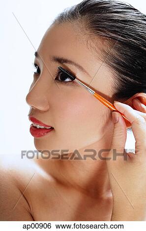 Woman applying mascara, looking away View Large Photo Image Stock Photograph - Woman applying mascara, looking away. Fotosearch