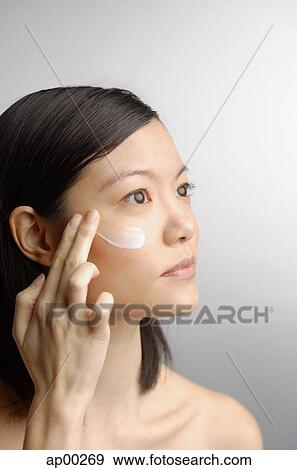 Woman applying moisturizer, side view View Large Photo Image Stock Photo - Woman applying moisturizer, side view. Fotosearch