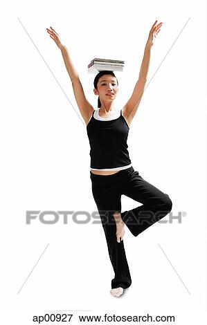 Stock Photo - Woman balancing books on her head, arms outstretched, standing on one leg. Fotosearch