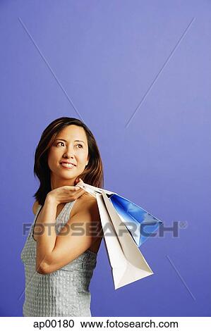 Stock Image - Woman carrying shopping bags over shoulder, looking away. Fotosearch