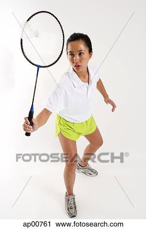 Stock Image - Woman hitting shuttlecock with badminton racket. Fotosearch
