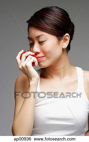 Stock Photograph - Woman holding apple, to her nose. Fotosearch