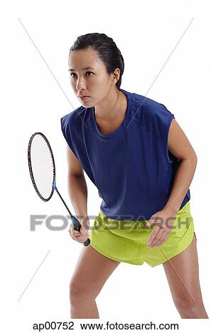 Stock Image - Woman holding badminton racket, looking forward. Fotosearch