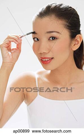 Stock Photo - Woman holding brush to eyebrows. Fotosearch