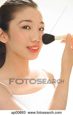 Woman holding make-up brush to face, looking at camera View Large Photo Image Stock Image - Woman holding make-up brush to face, looking at camera. Fotosearch